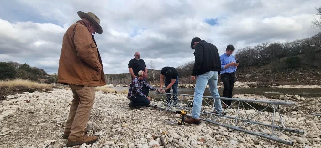 Crew assembling a metal lattice tower for a South Fork Guadalupe River flood monitoring and early warning gage.