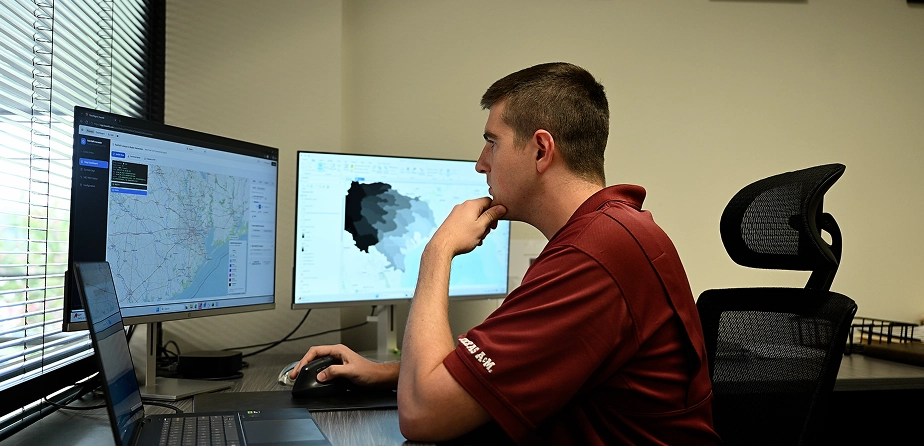 Engineer analyzing GIS flood maps across multiple monitors