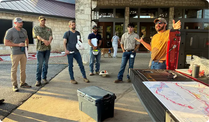 Engineer briefing a field team over a floodplain map at a truck tailgate